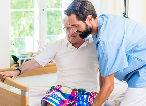 Personal Support Worker Helping an Elderly Nursing Home Patient Out of Bed